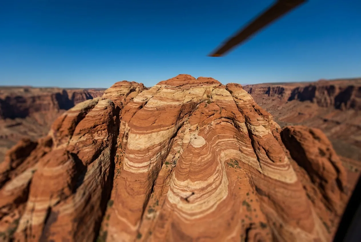 Aerial view of Red Rock Canyon's banded sandstone ridges from a helicopter under a clear desert sky